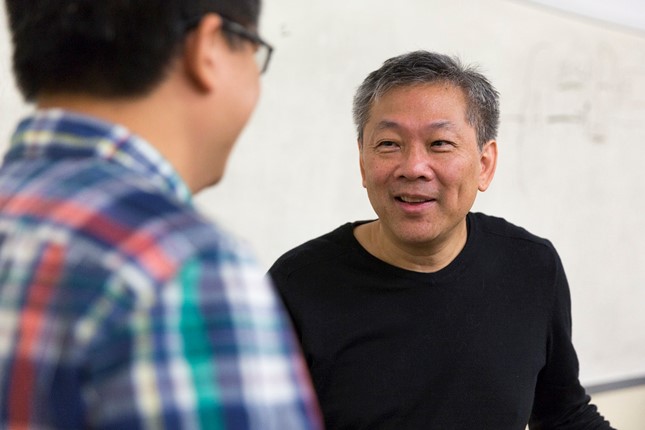 Professor Menzie Chinn talks with someone in front of a whiteboard