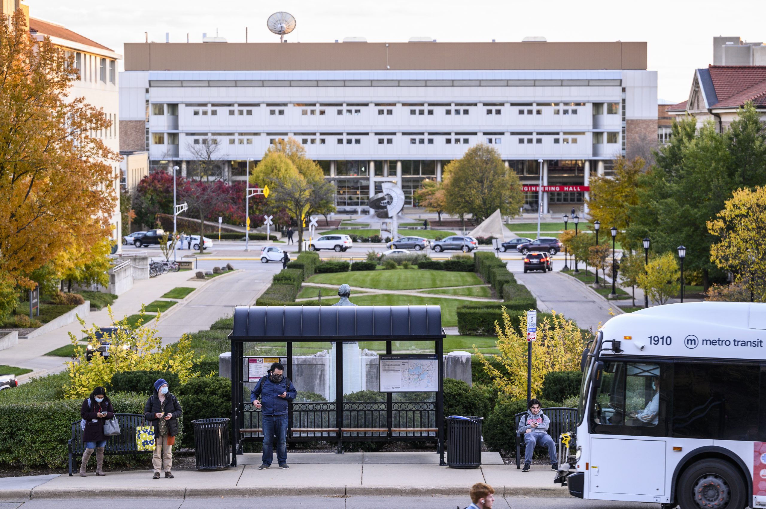 SPeople waiting at a bus stop on campus.