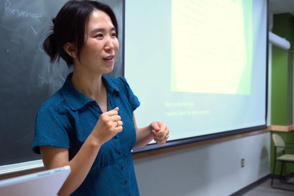 Associate Professor Yang Wang delivers a lecture in front of a chalkboard