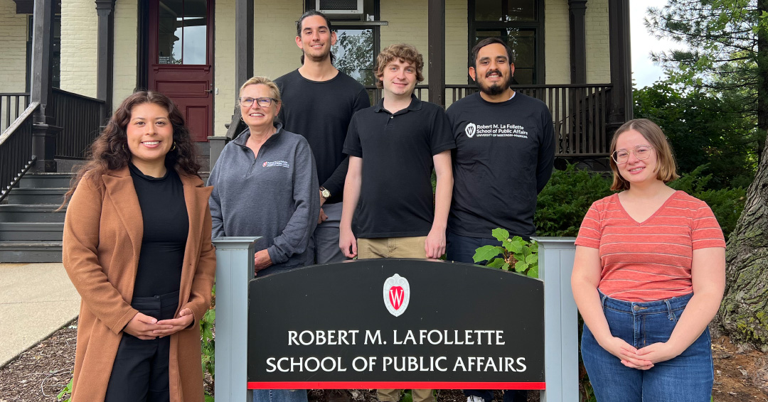 Student association board members stand next to a sign for the La Follette School.