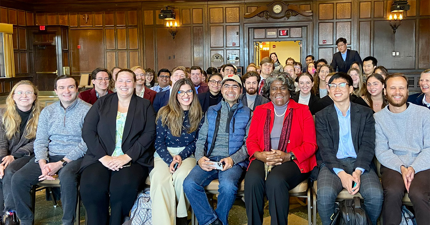 Ambassador Linda Thomas-Greenfield sits smiling, surrounded by students.