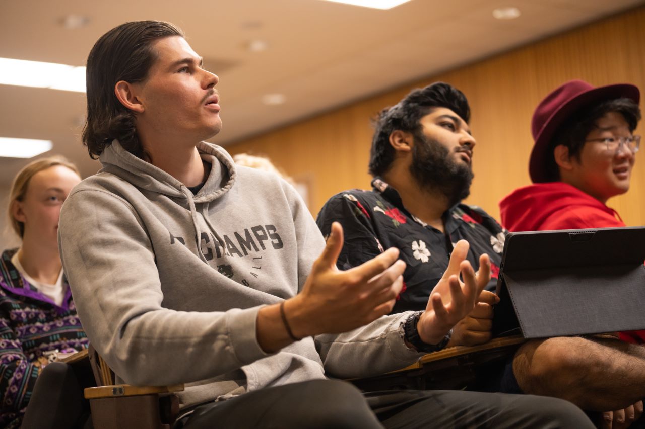 Student gestures with their hands while asking a question.