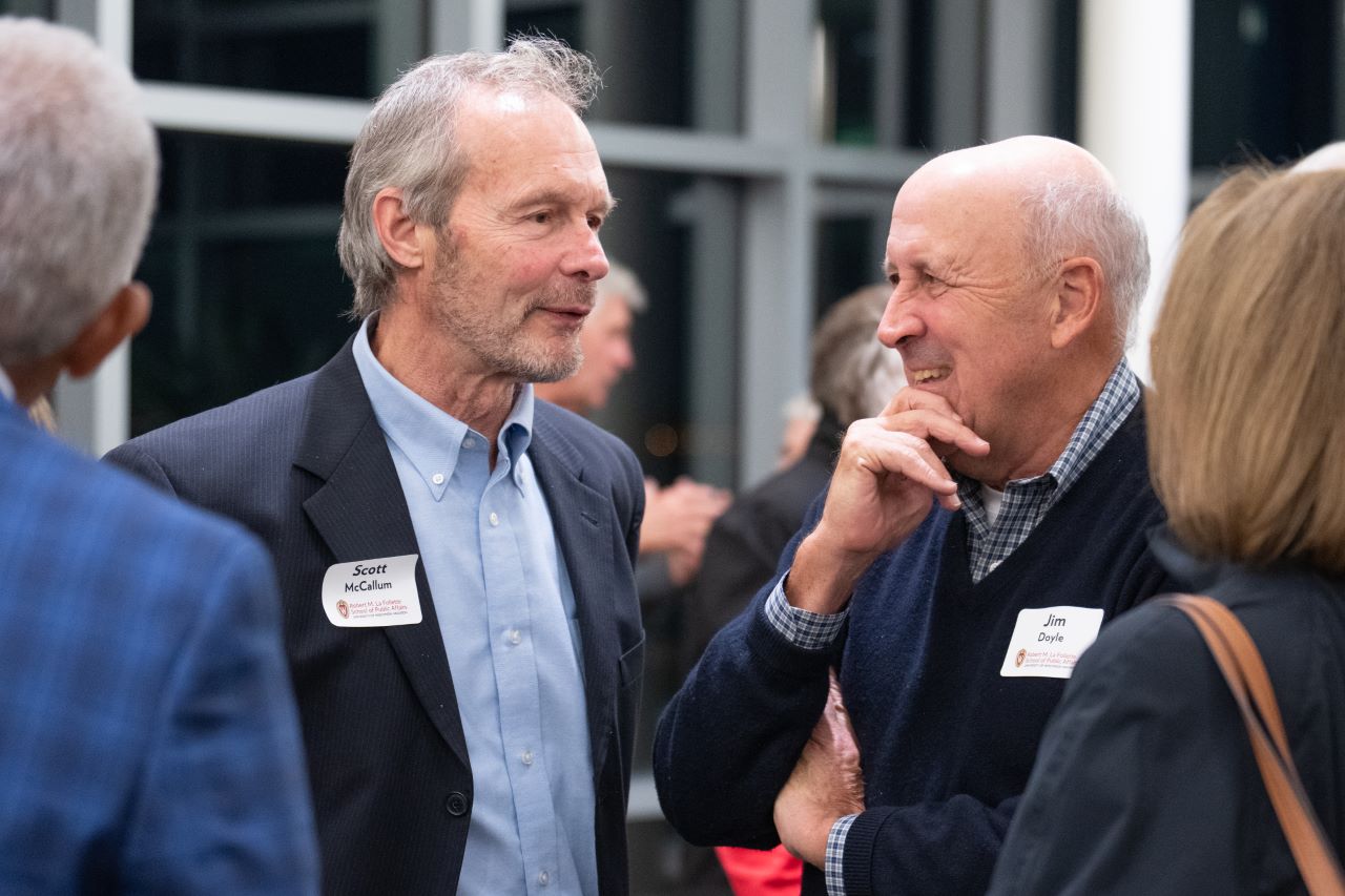 Two men stand and talk during a reception.