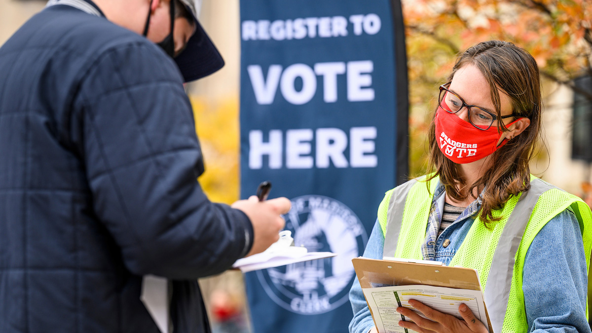 At right, Ann Elise Trafford, with the City of Madison Clerk’s Office, helps students register to vote ahead of the presidential election while staffing an information table on East Campus Mall at the University of Wisconsin-Madison.