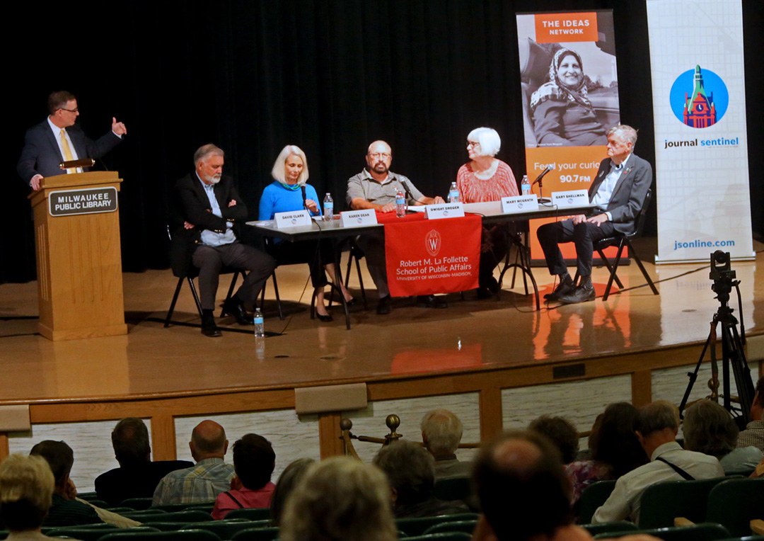 Jim Fitzhenry stands at a podium and addresses the citizen panel.