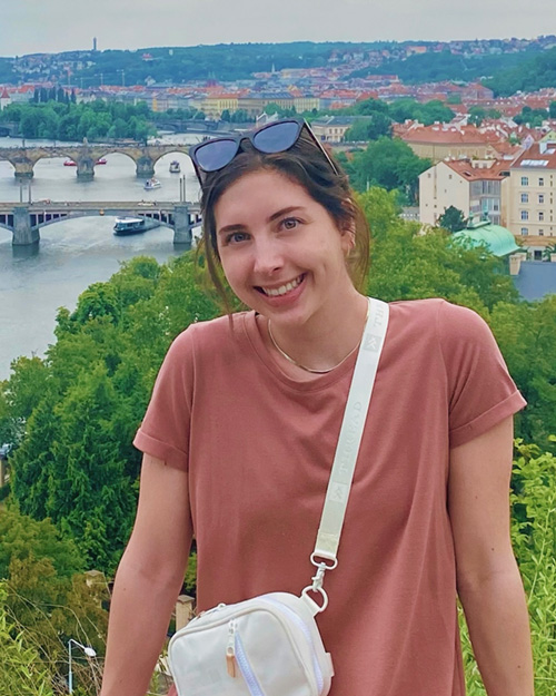 Photo of certificate graduate Kaylin Hewitt in front of a view of a river and town.