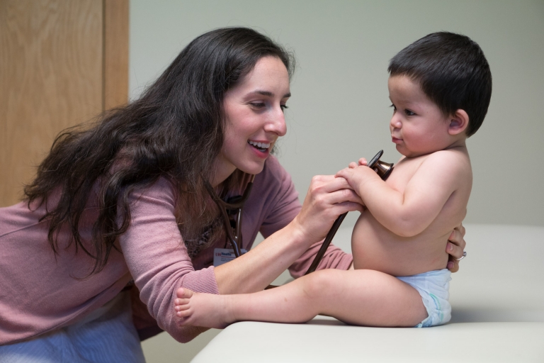 Allison Couture checks the heartbeat of an infant using a stethoscope.