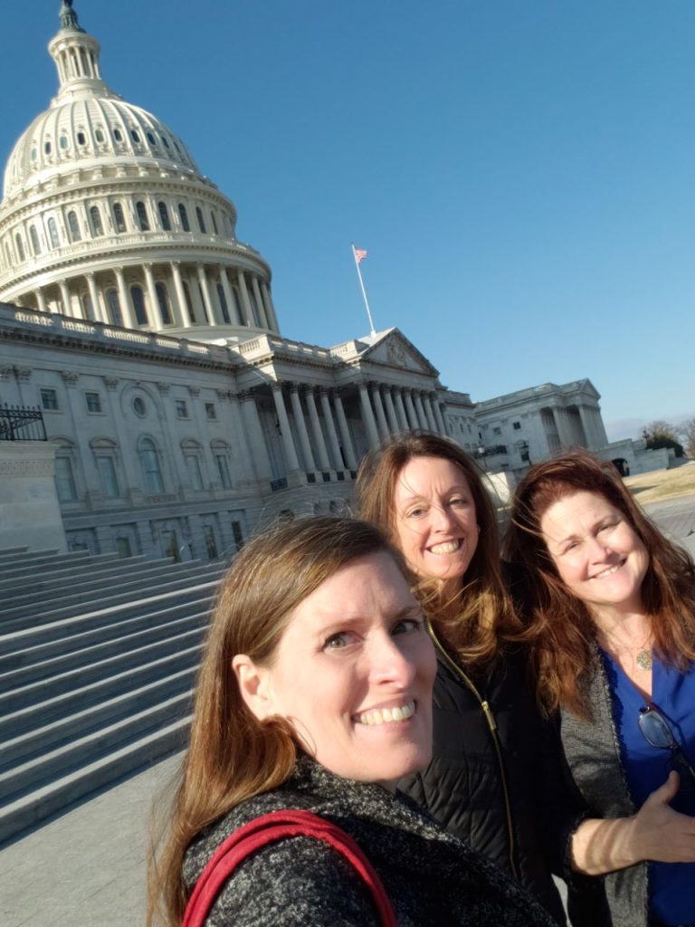 Outreach staff take a selfie in front of the U.S. Capitol.