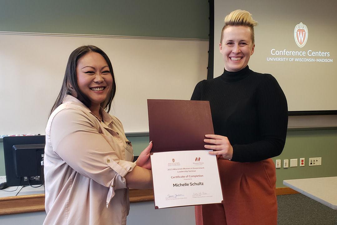 Mariel Barnes hands attendee Michelle Schultz a certificate.