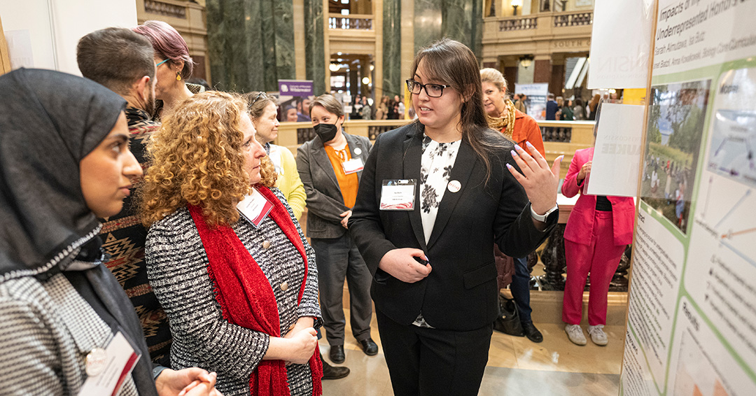 Certificate student Isa Butz gestures towards a poster while Chancellor Mnookin listens