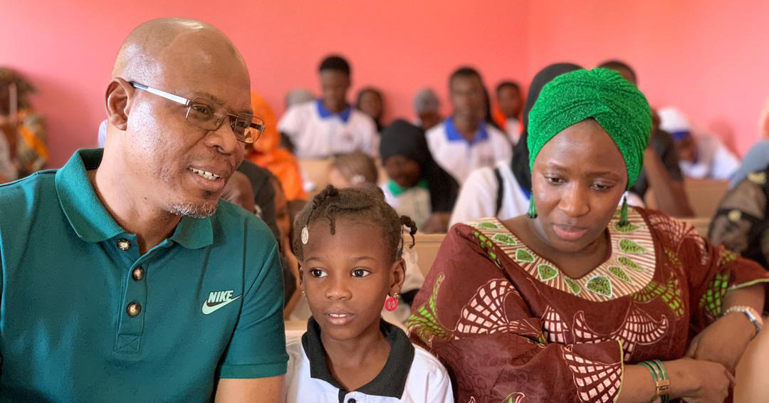 Parents sit on either side of their child, who is a student in Mali.