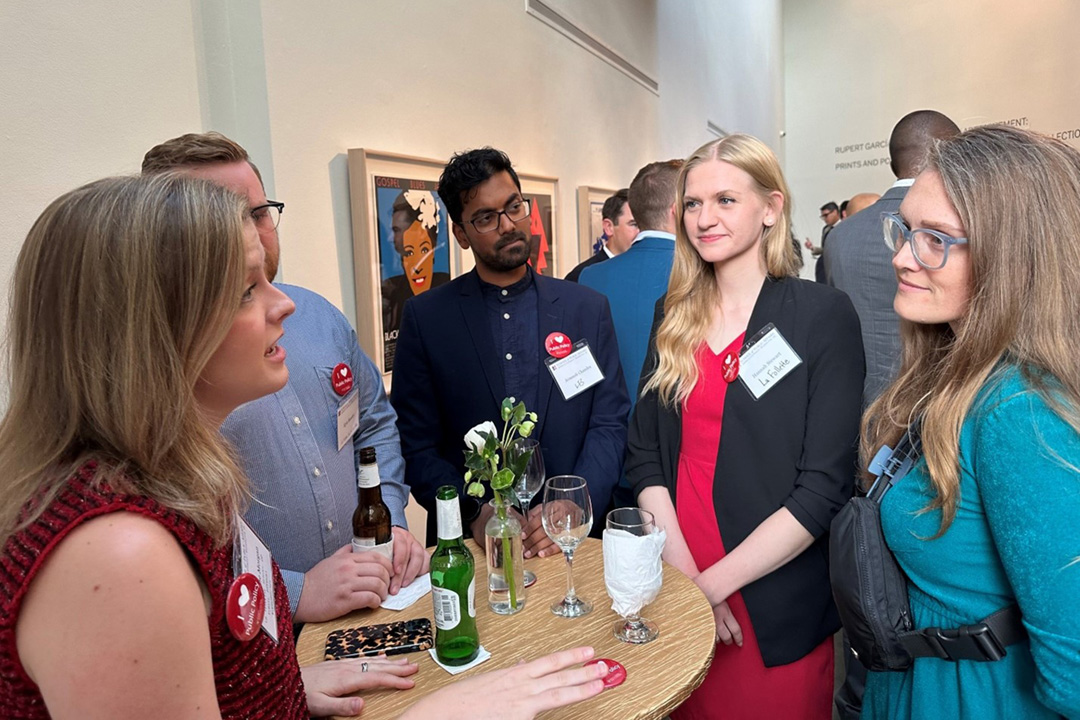 Alumni stand around a high table, socializing at an event
