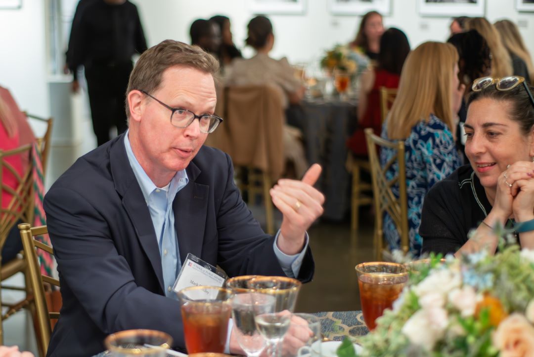 Mark Hadley speaks to an attendee across the table