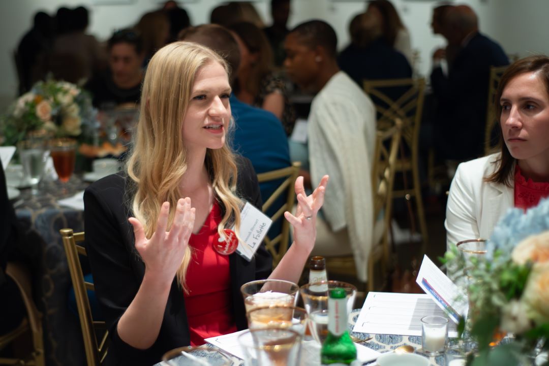 Hannah Stewart gestures while talking to other attendees at the table.
