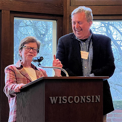 Rebecca Blank standing at a podium next to a laughing Tim Smeeding