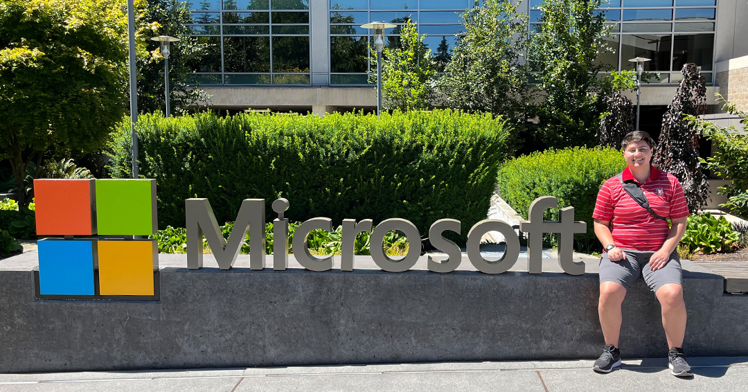Cameron Yonan sits next to a sign for Microsoft