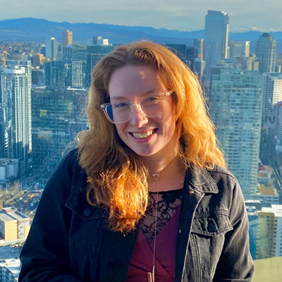 Genevieve Kell stands in front of a view of a city skyline with skyscrapers