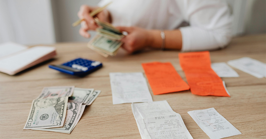A person reviews receipts and counts cash.