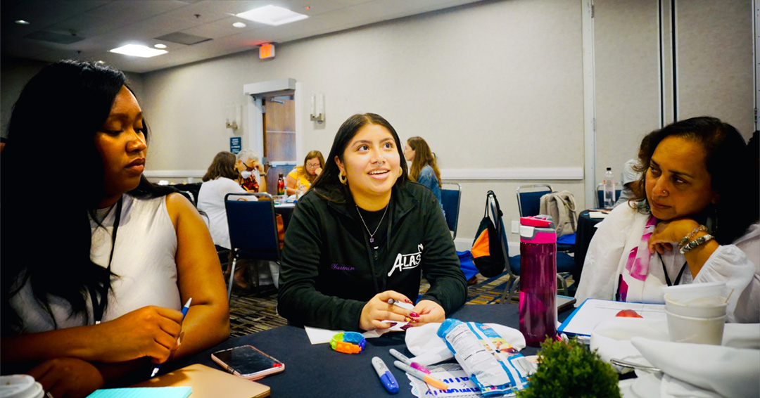Carte'cia Weaver sits at a table with two other forum attendees.