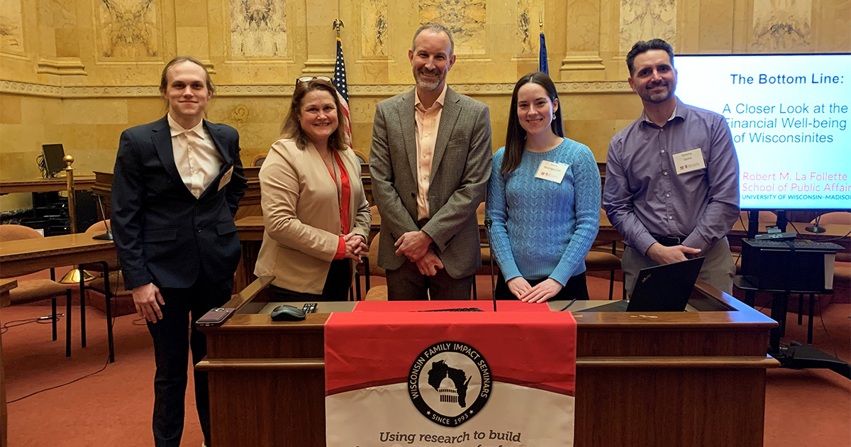J. Michael Collins stands with La Follette School students and faculty in front of a Family Impact Seminar banner in the Wisconsin State Capitol