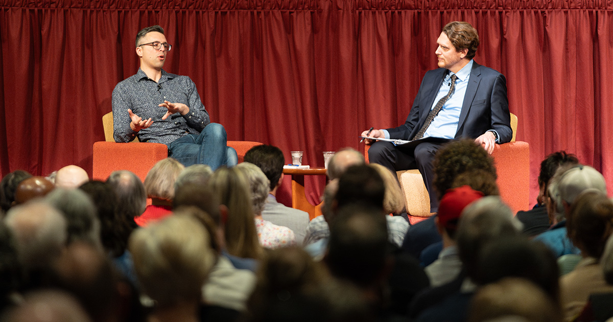 Ezra Klein and Greg Nemet sit on a stage in the Monona Terrace