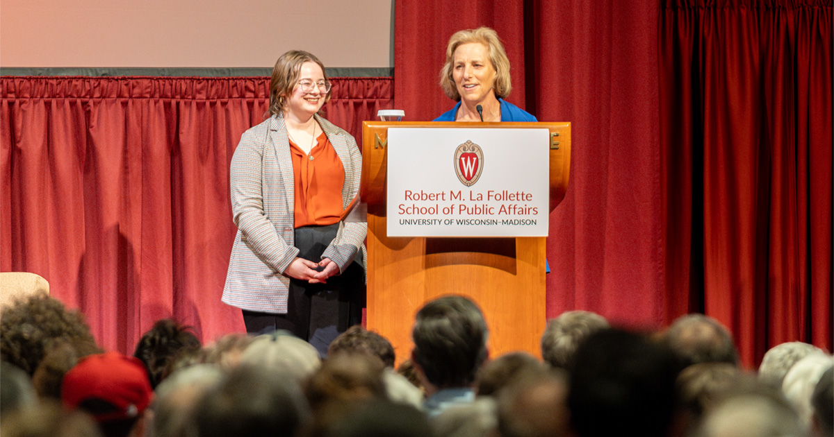 Justice Jill Karofsky and MPA student Johanna Schmidt stand at a podium in front of an audience in the Monona Terrace