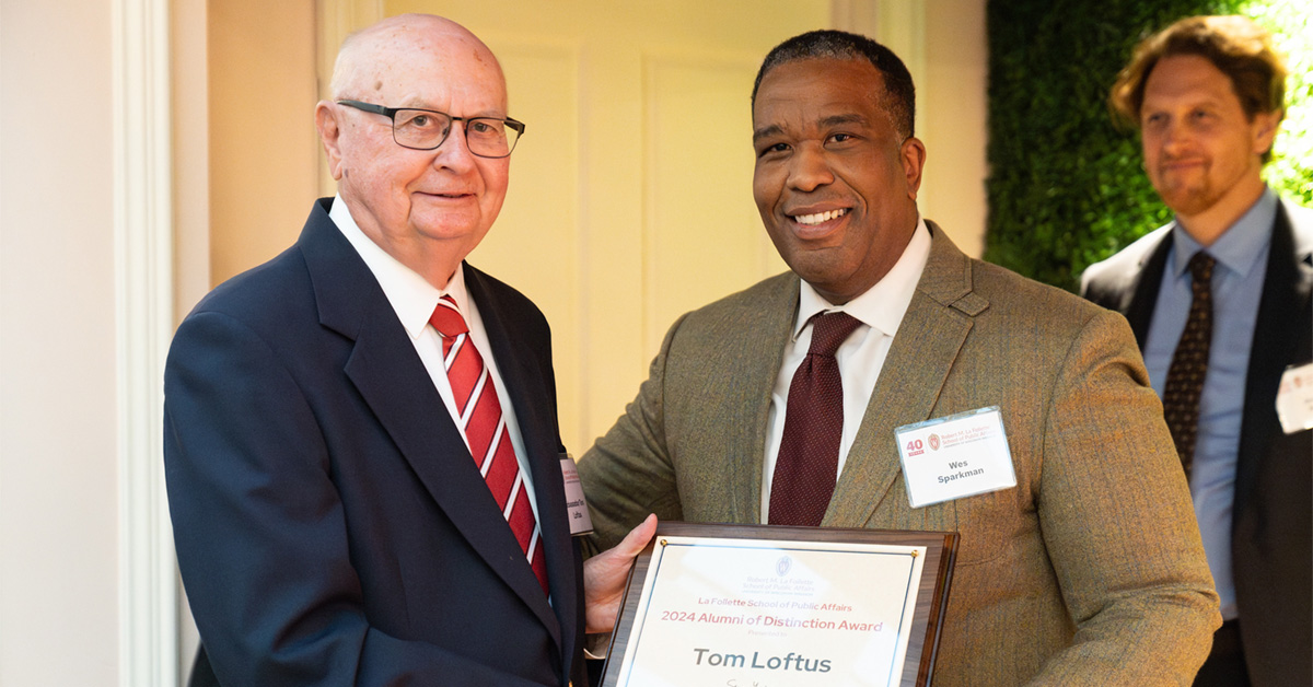 Wesley Sparkman hands a plaque to Tom Loftus at a reception.
