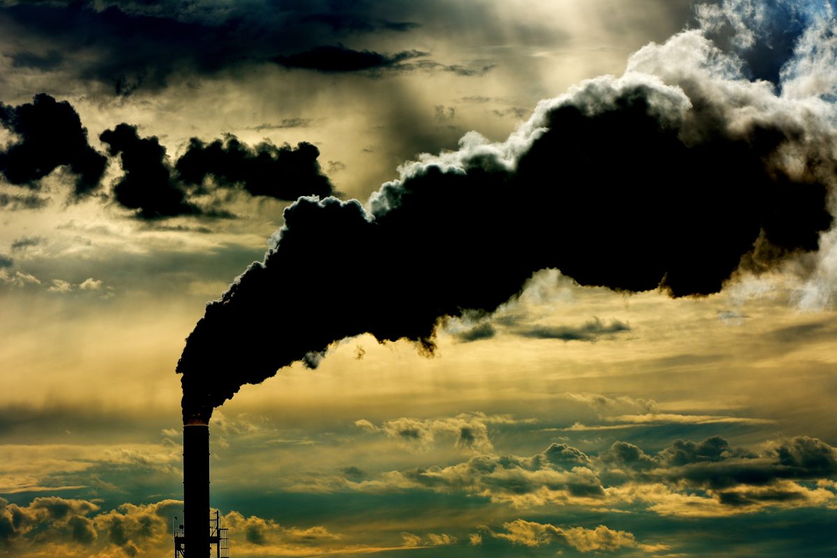Silhouette of smokestack with clouds in the background
