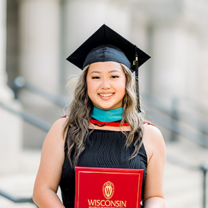 Hnub Xiong poses with diploma on the steps to the Capitol building