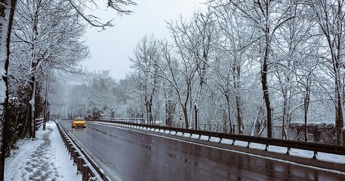 A taxi drives down a snowy street