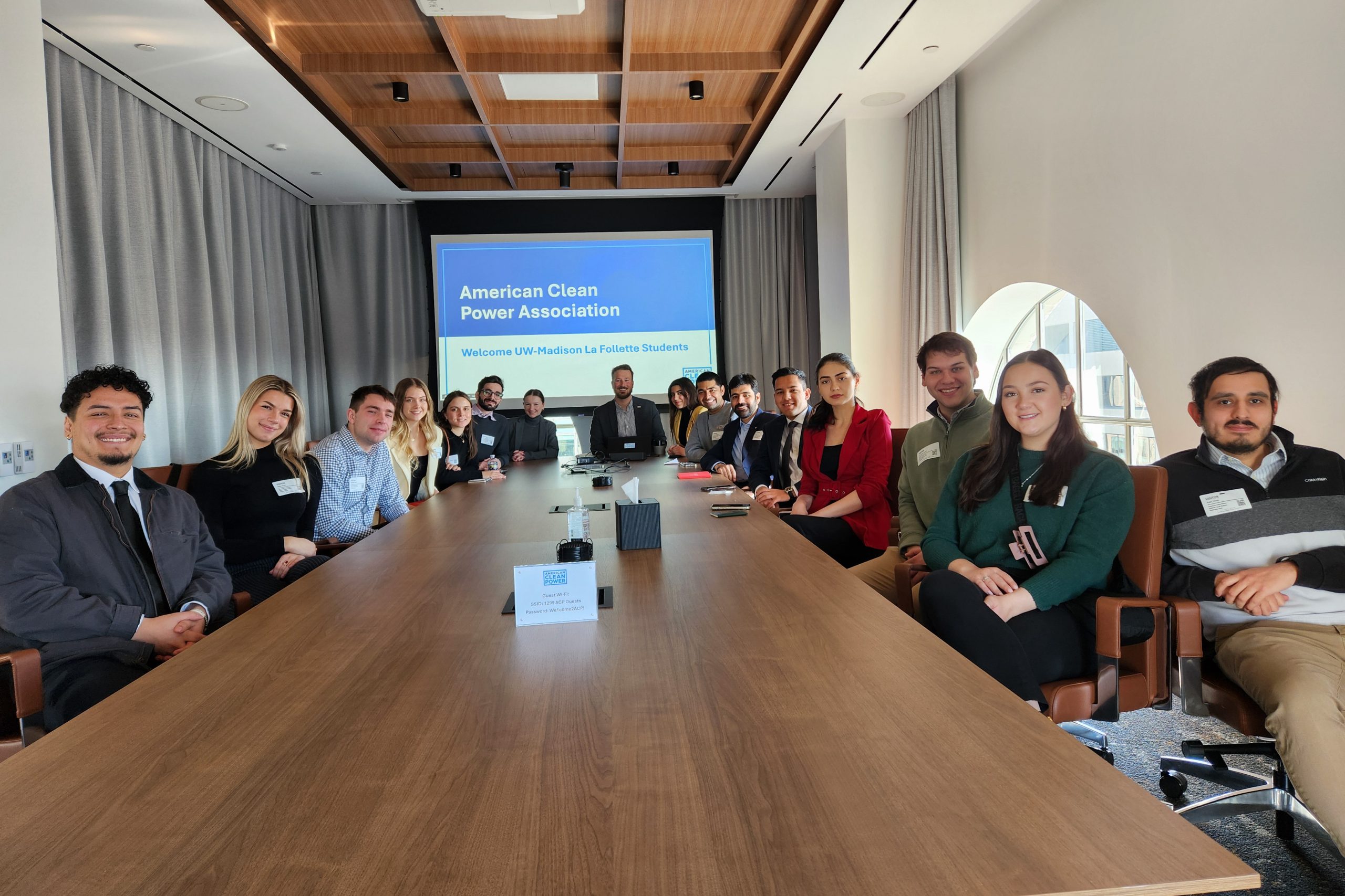 Students pose for a photo around a conference table