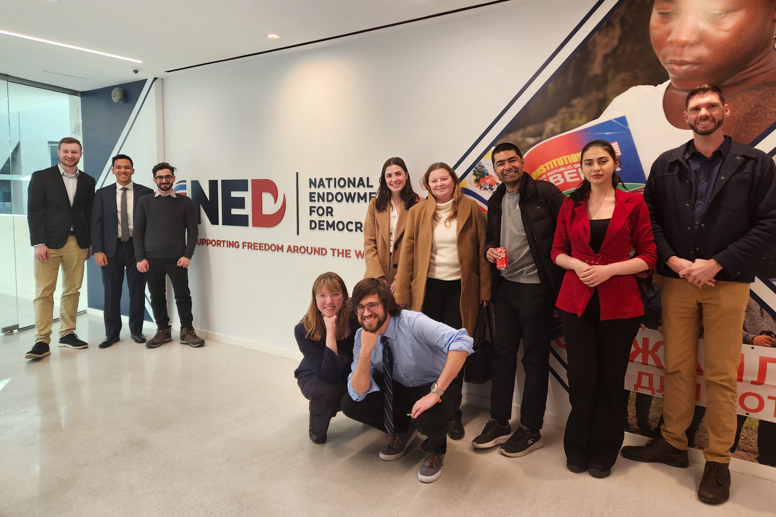 Students stand in front of a sign that says "National Endowment for Democracy"