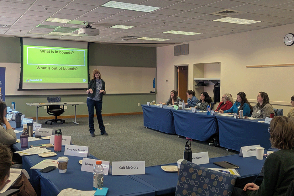 Audience members sit around tables as a presenter speaks