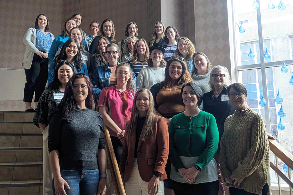 Seminar participants pose for a photo standing on stairs