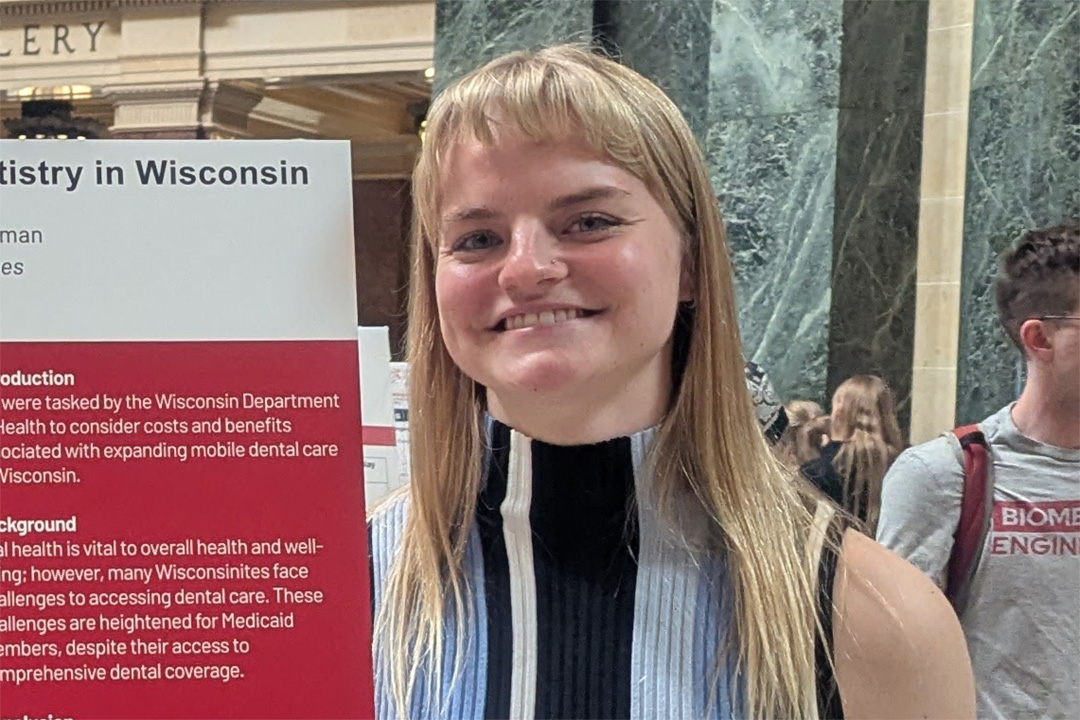 Alivia Lindorfer stands next to her poster in the Wisconsin State Capitol.