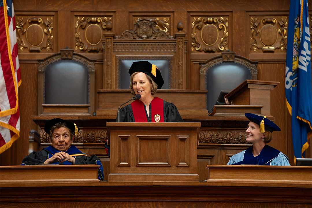 Jill Karofsky speaks at podium with Donna Shalala and Susan Yackee looking on