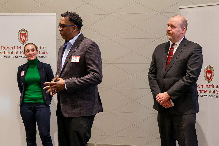 Steven Little presents at an event while Randy Romanski and Mikhaila Calice listen.