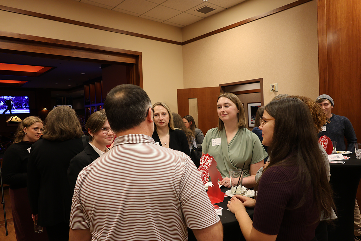 Five people gather around a standing table at the event talking.
