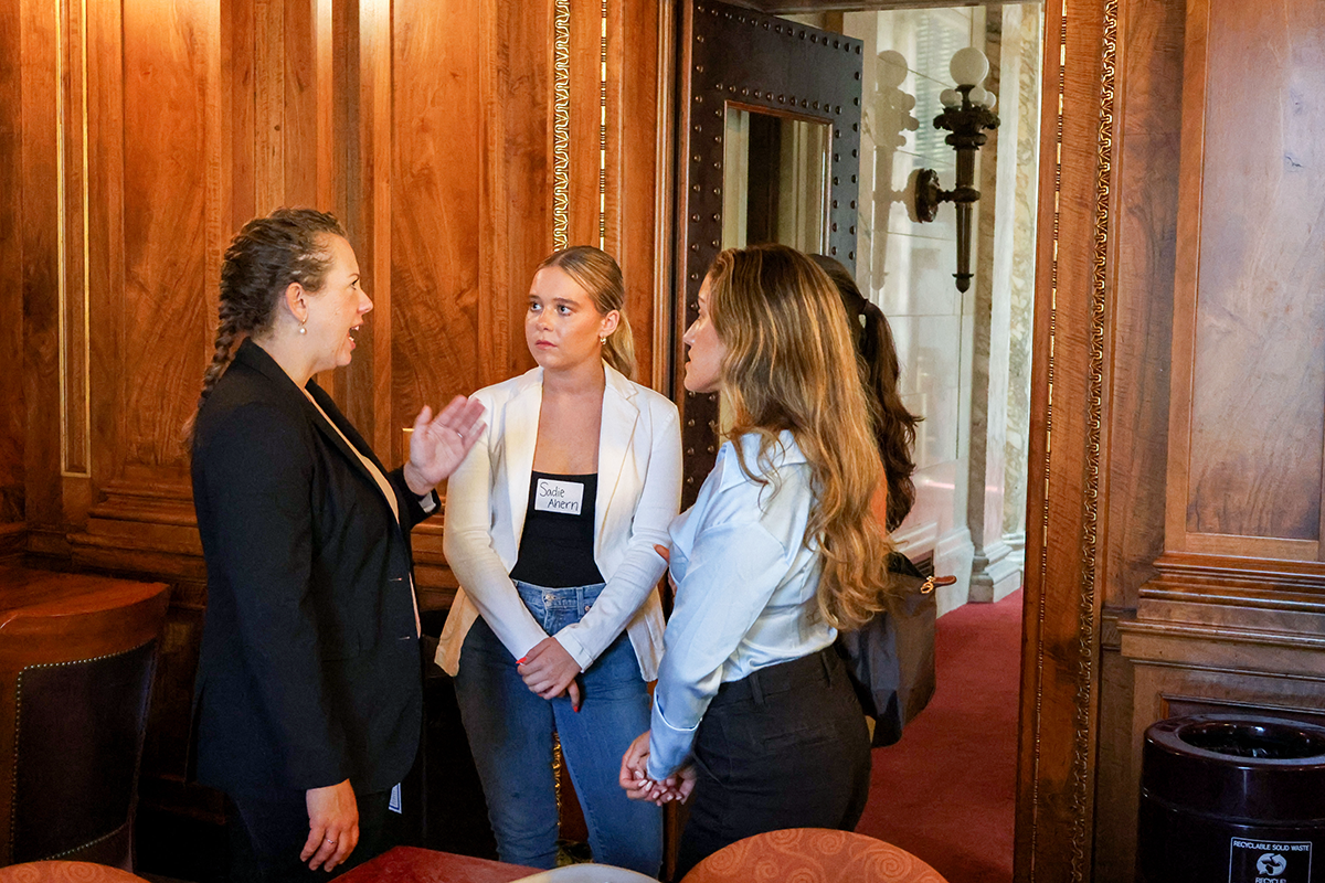 Christa Pugh chatting with 2 students, offering advice, inside the capitol.