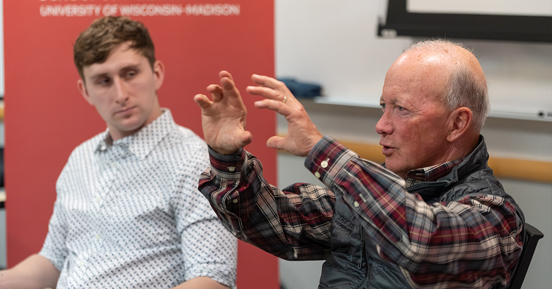 Mitch Daniels gestures while explaining a point while students observe.