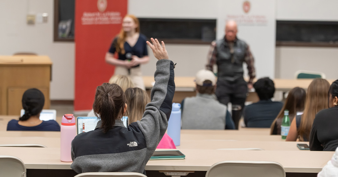 A student raises their hand in an undergraduate class.