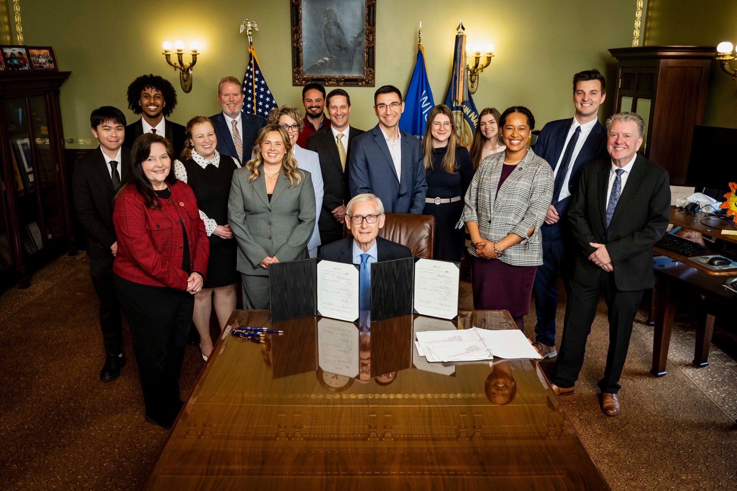 La Follette students surround Governor Evers smiling while he holds the new bill.