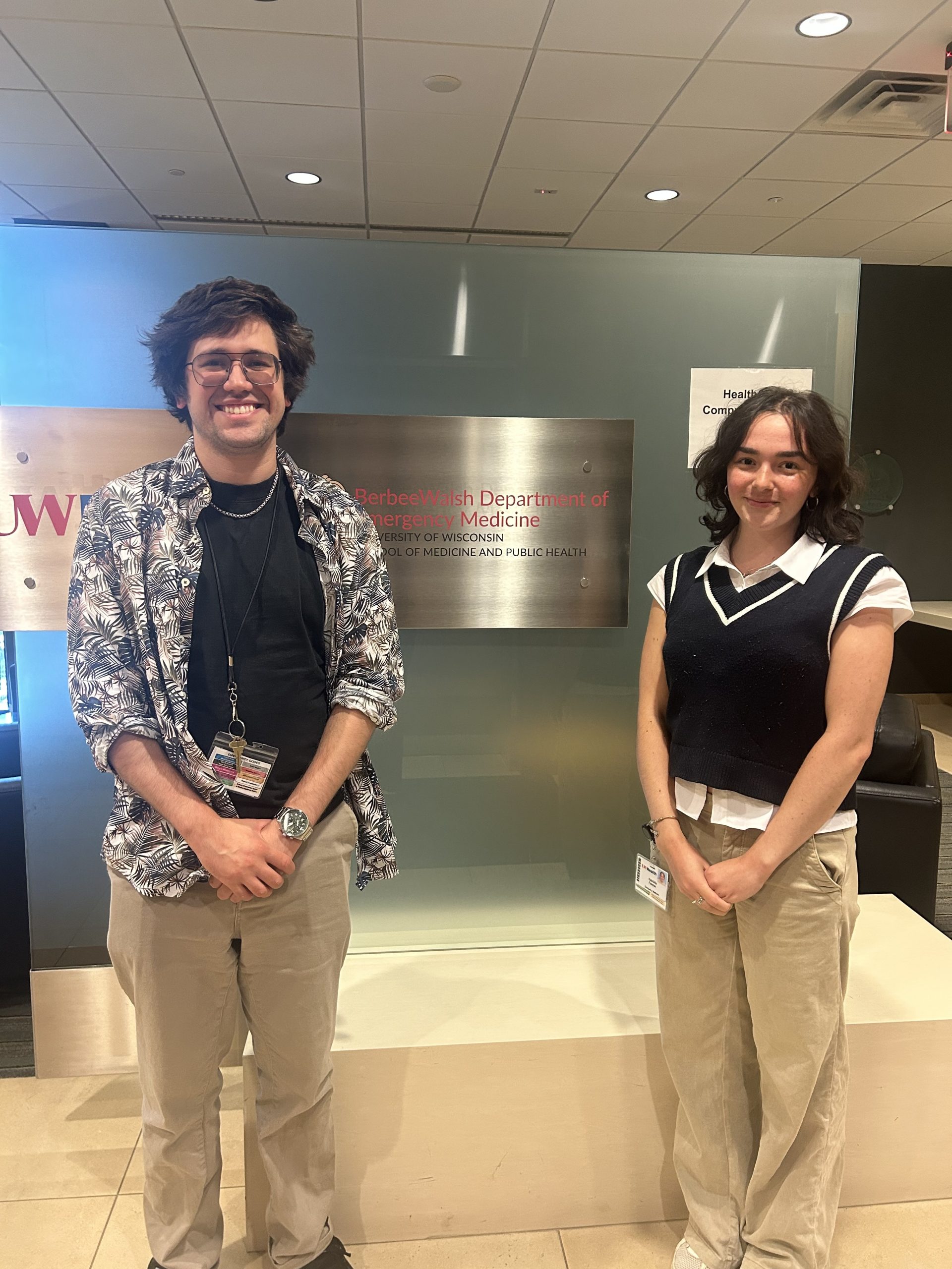 Student and mentor stand beside sign.