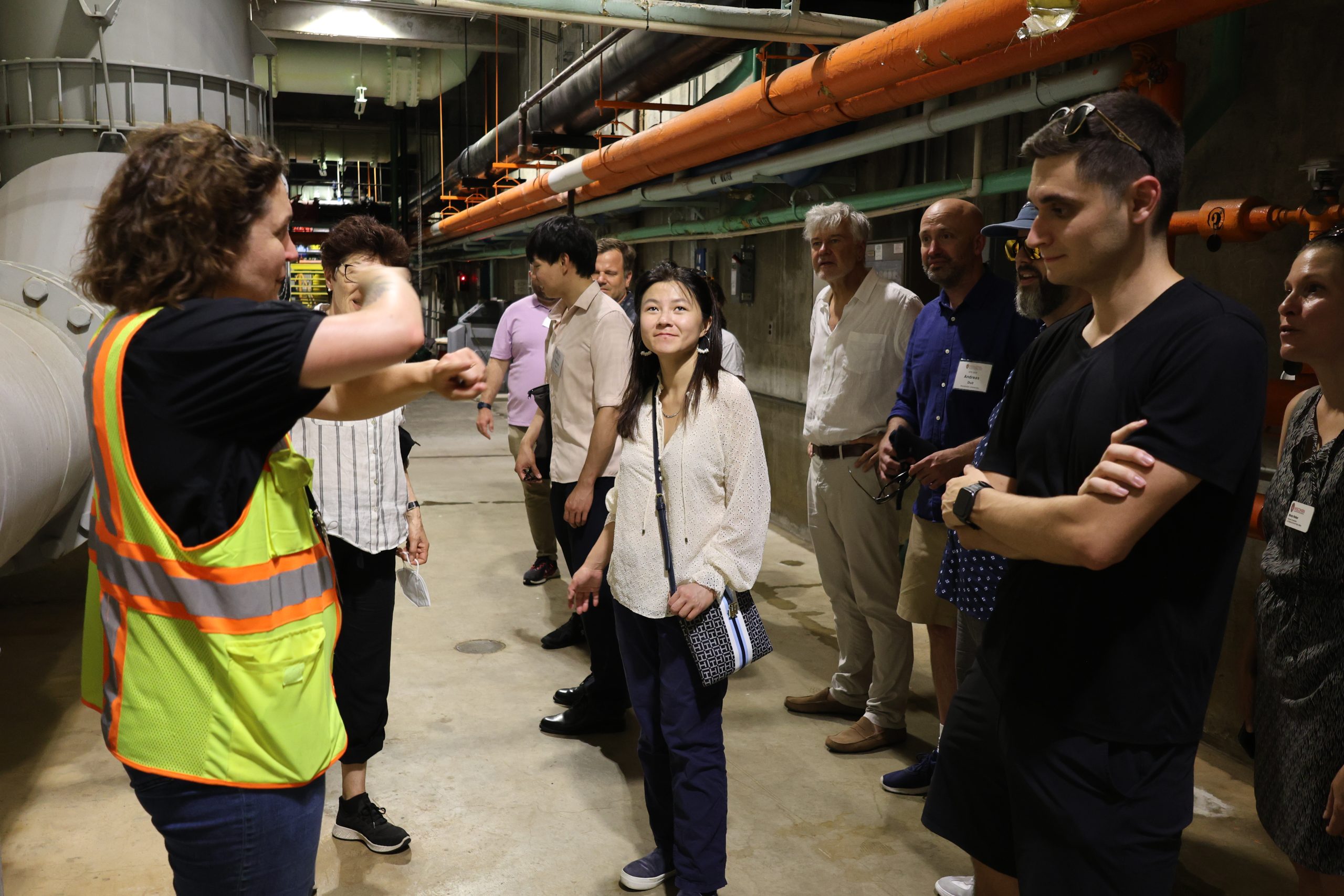 People stand in a tunnel with pipes and equipment
