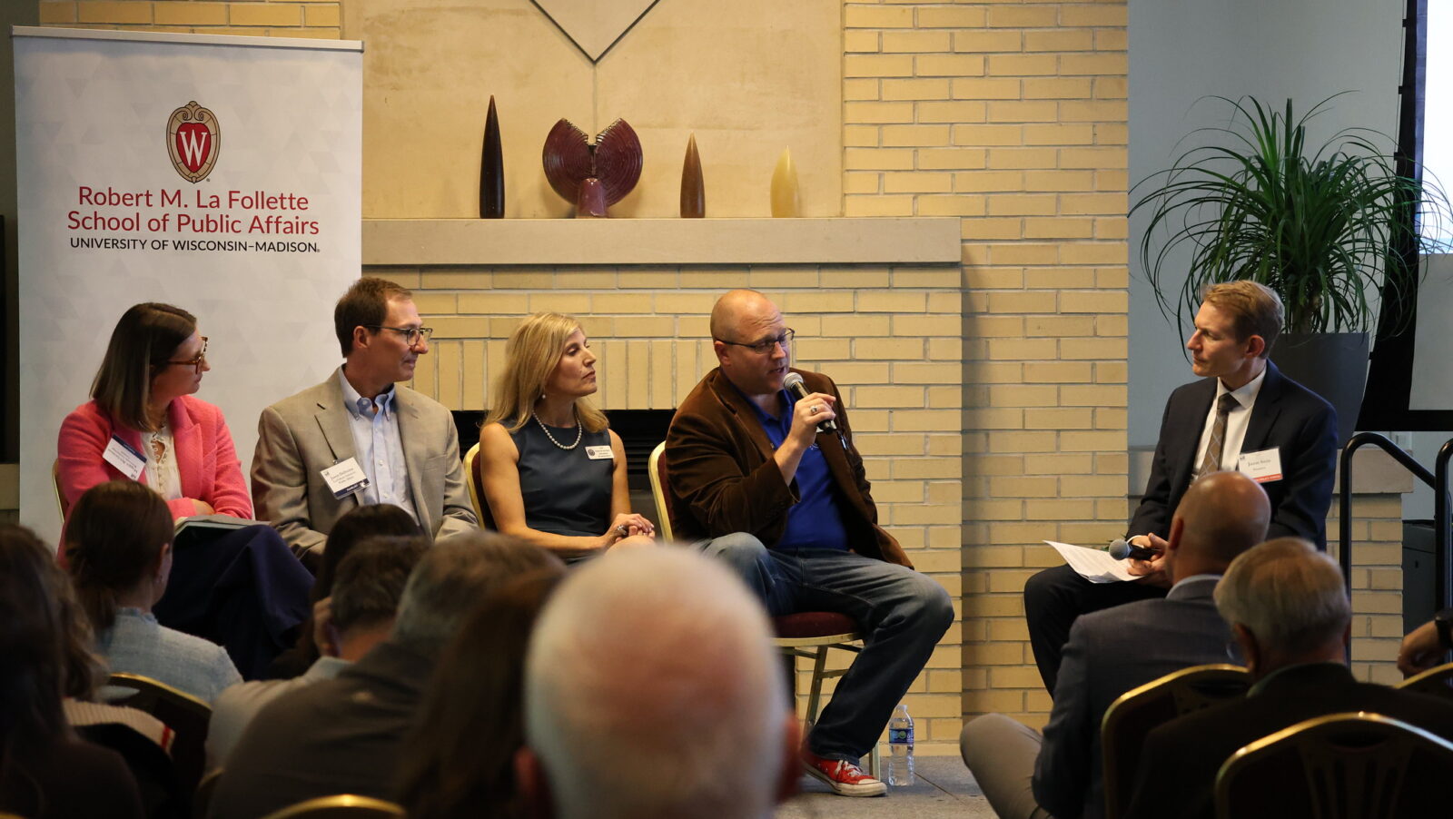 Four panelists sit at the front of an audience with a moderator.