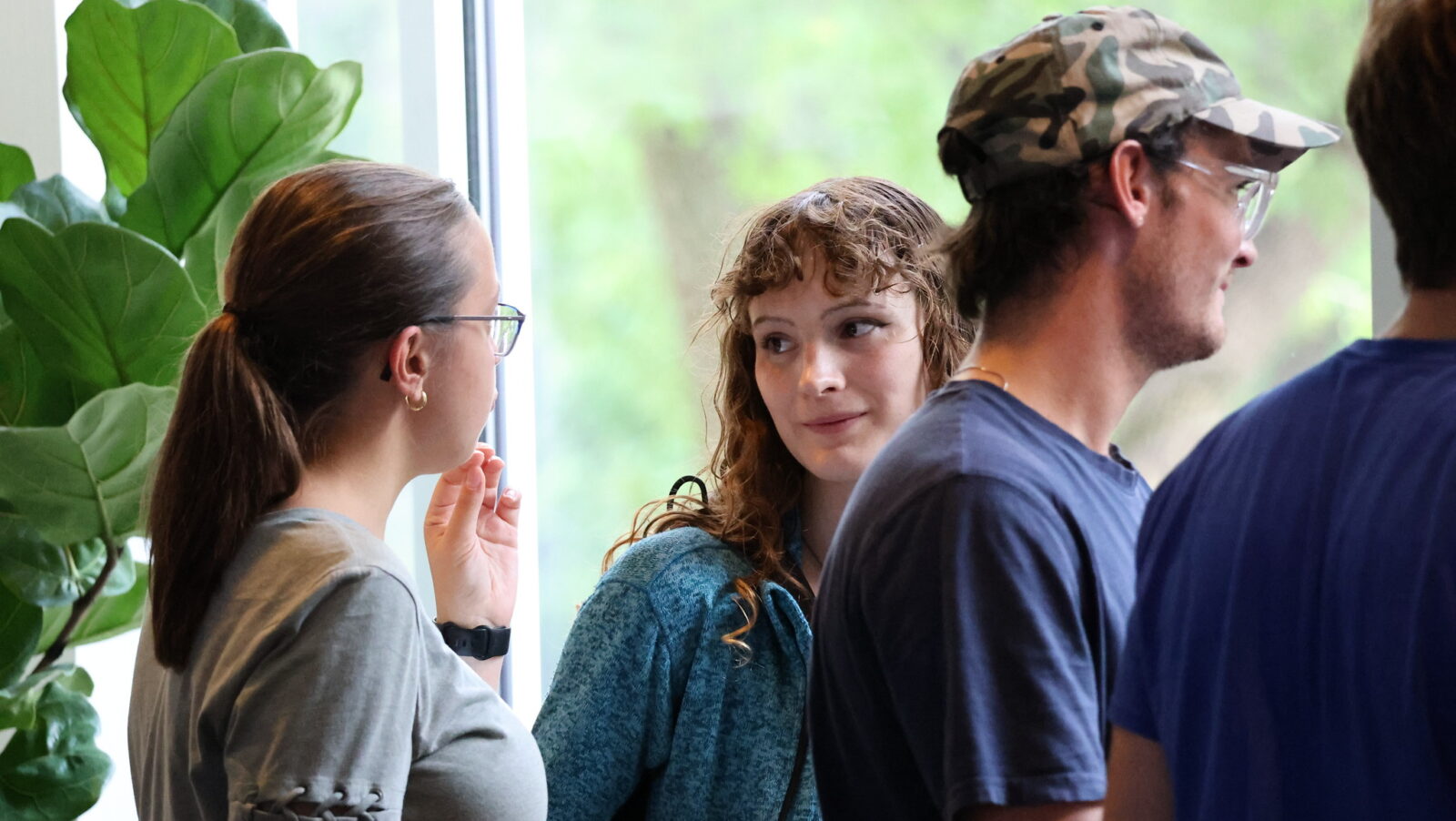 Students talk in front of a window