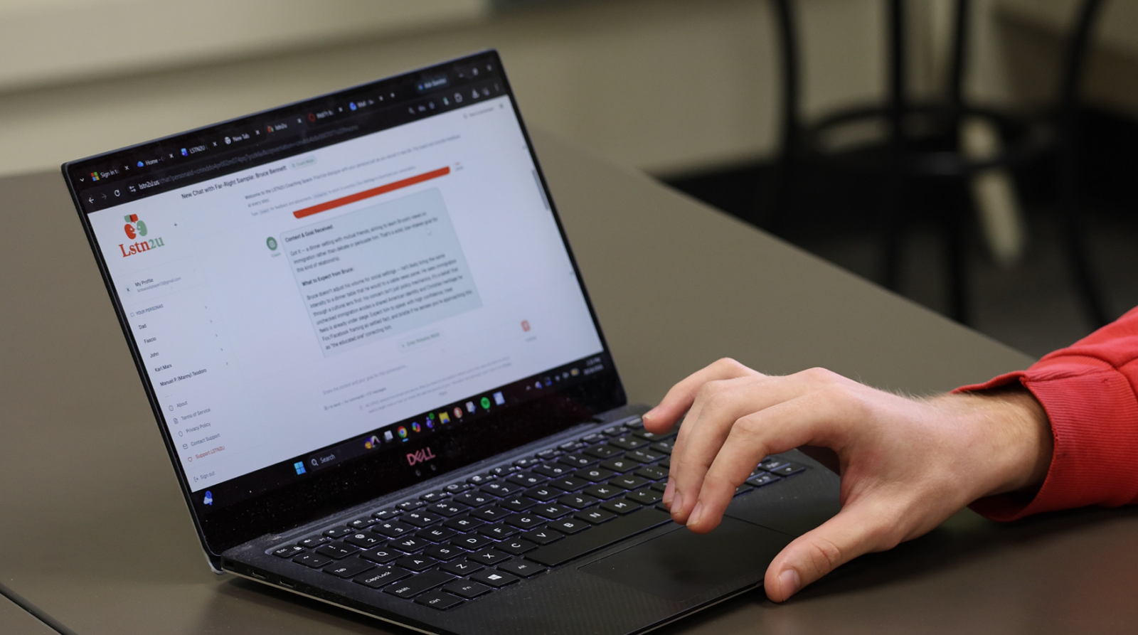 A hand types on a laptop keyboard with the LSTN2U website on screen.